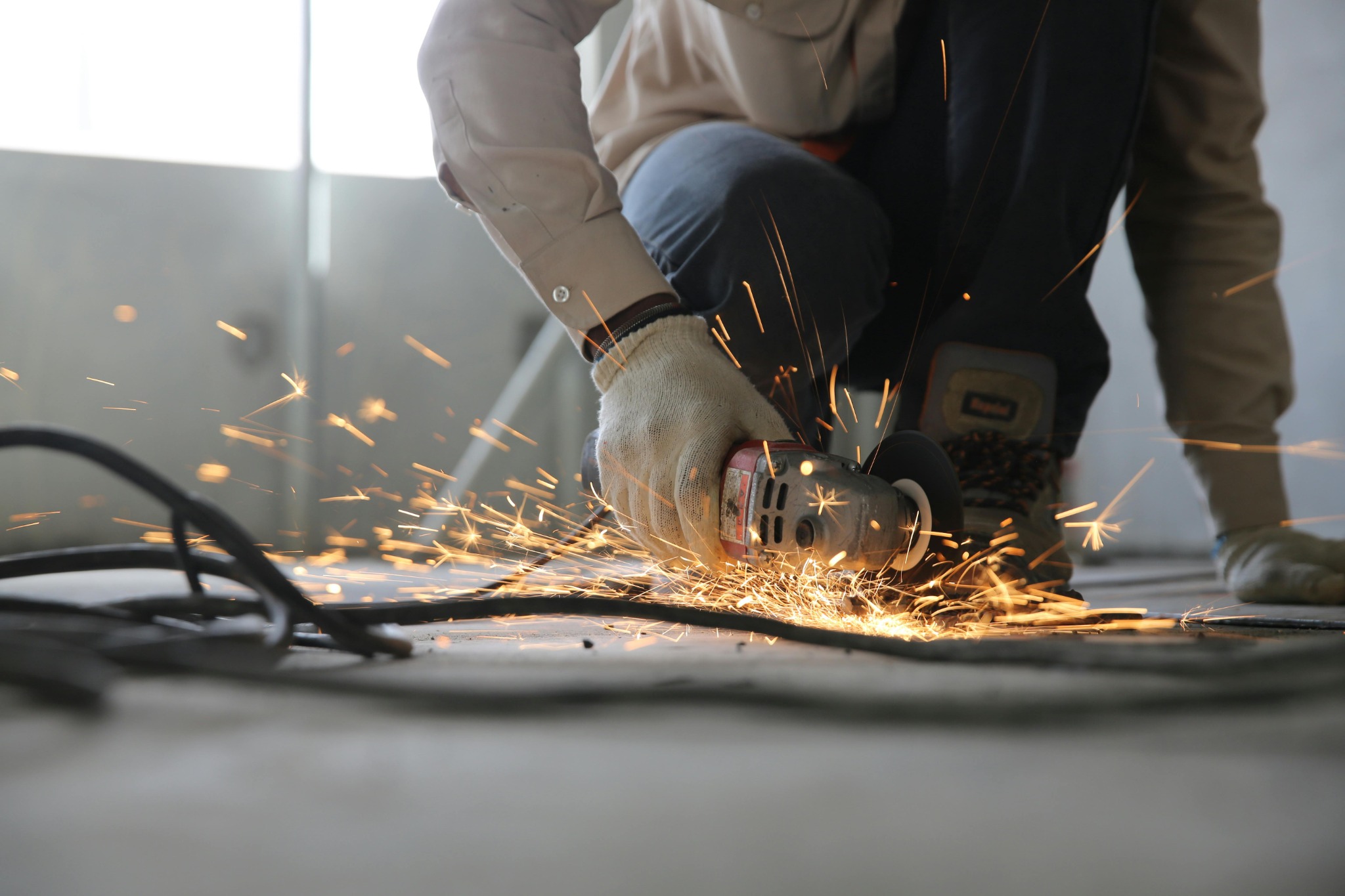 Worker using an angle grinder inside a building during refurbishment